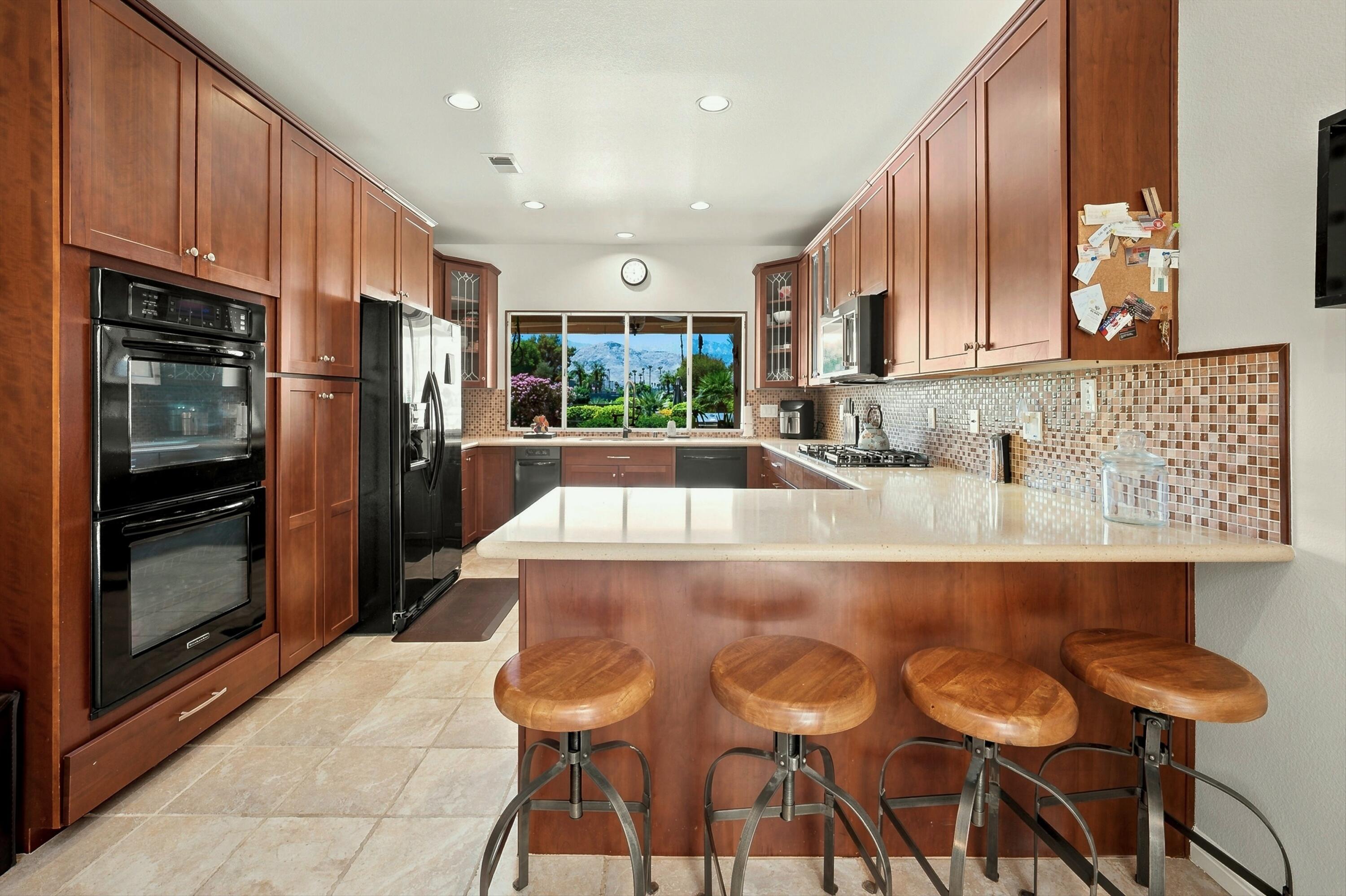138 Lakeshore Drive Rancho Mirage, CA 92270 - Photo 7 of 30 a kitchen with kitchen island granite countertop a table chairs microwave and cabinets