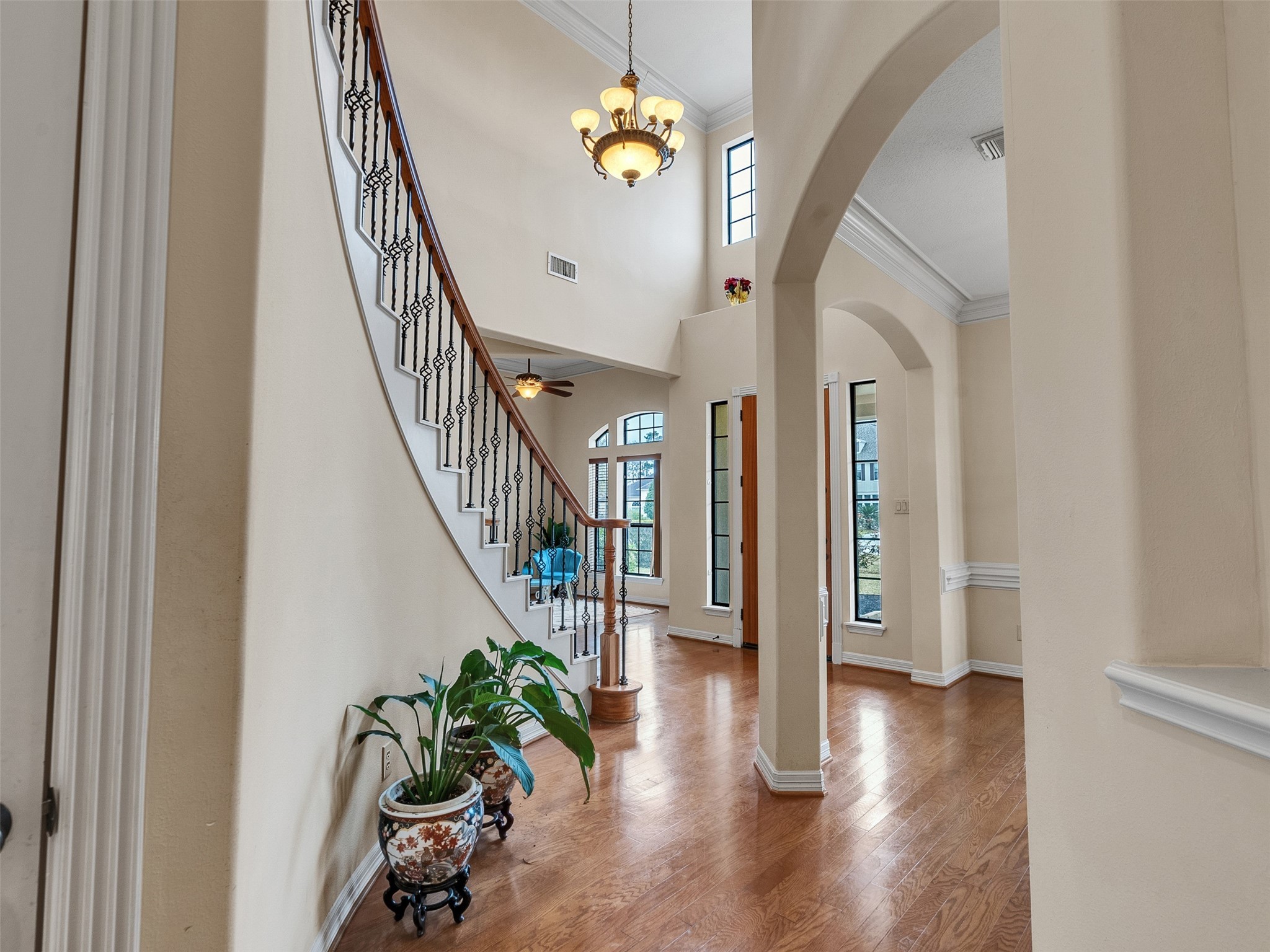 6914 Sandwedge Point Court Spring, TX 77389 - Photo 15 of 50 This elegant entryway features a grand curved staircase with wrought iron railings, hardwood floors, and high ceilings. Large windows provide ample natural light, while arched doorways add a touch of sophistication.