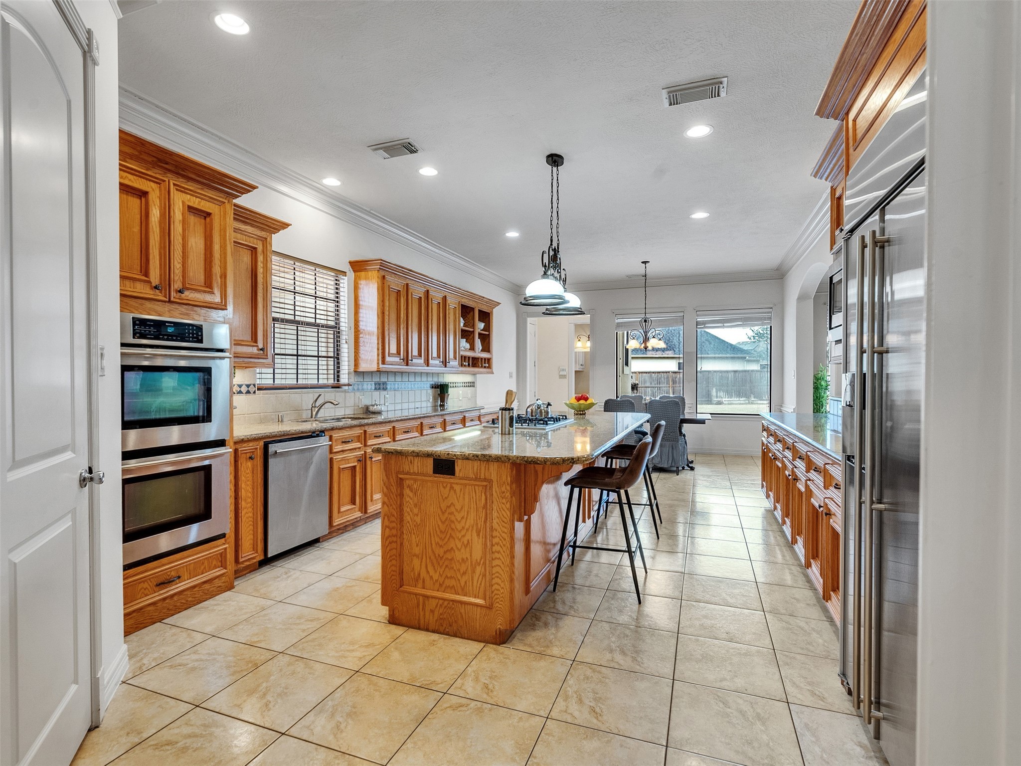 6914 Sandwedge Point Court Spring, TX 77389 - Photo 26 of 50 Bright and spacious kitchen with ample natural light, featuring wooden cabinetry, granite countertops, stainless steel appliances, and a central island with seating. Ideal for cooking and entertaining.