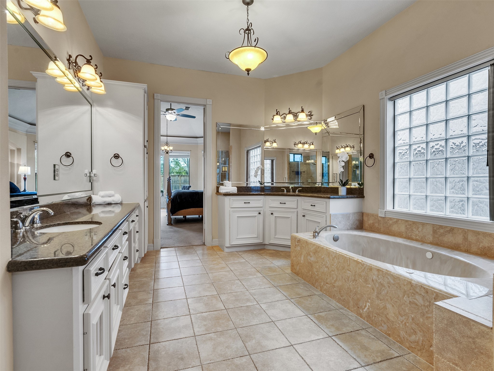 6914 Sandwedge Point Court Spring, TX 77389 - Photo 35 of 50 This spacious bathroom features a luxurious soaking tub, dual sinks with granite countertops, and ample lighting. It boasts large mirrors, elegant fixtures, and a frosted glass window for natural light and privacy.