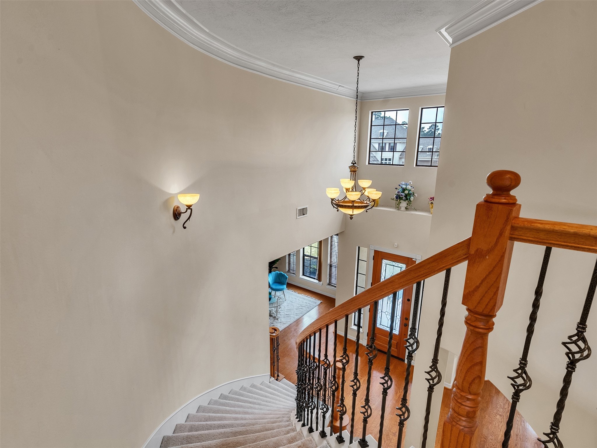 6914 Sandwedge Point Court Spring, TX 77389 - Photo 38 of 50 This elegant foyer features a curved staircase with wooden handrails and iron spindles, leading to a bright, two-story entryway. A stylish chandelier and large windows provide ample natural light, highlighting the open layout and warm hardwood floors below.
