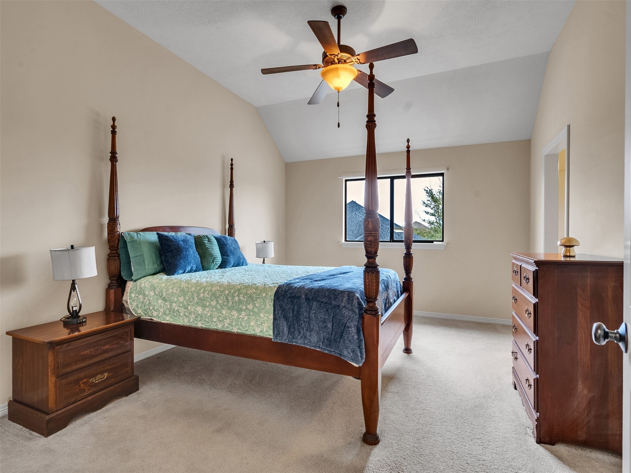 6914 Sandwedge Point Court Spring, TX 77389 - Photo 39 of 50 This bedroom features a high ceiling with a ceiling fan, a large window providing natural light, and is furnished with a four-poster bed, nightstand, and dresser, all in rich wood tones. The neutral walls and carpet add to the spacious and inviting atmosphere.