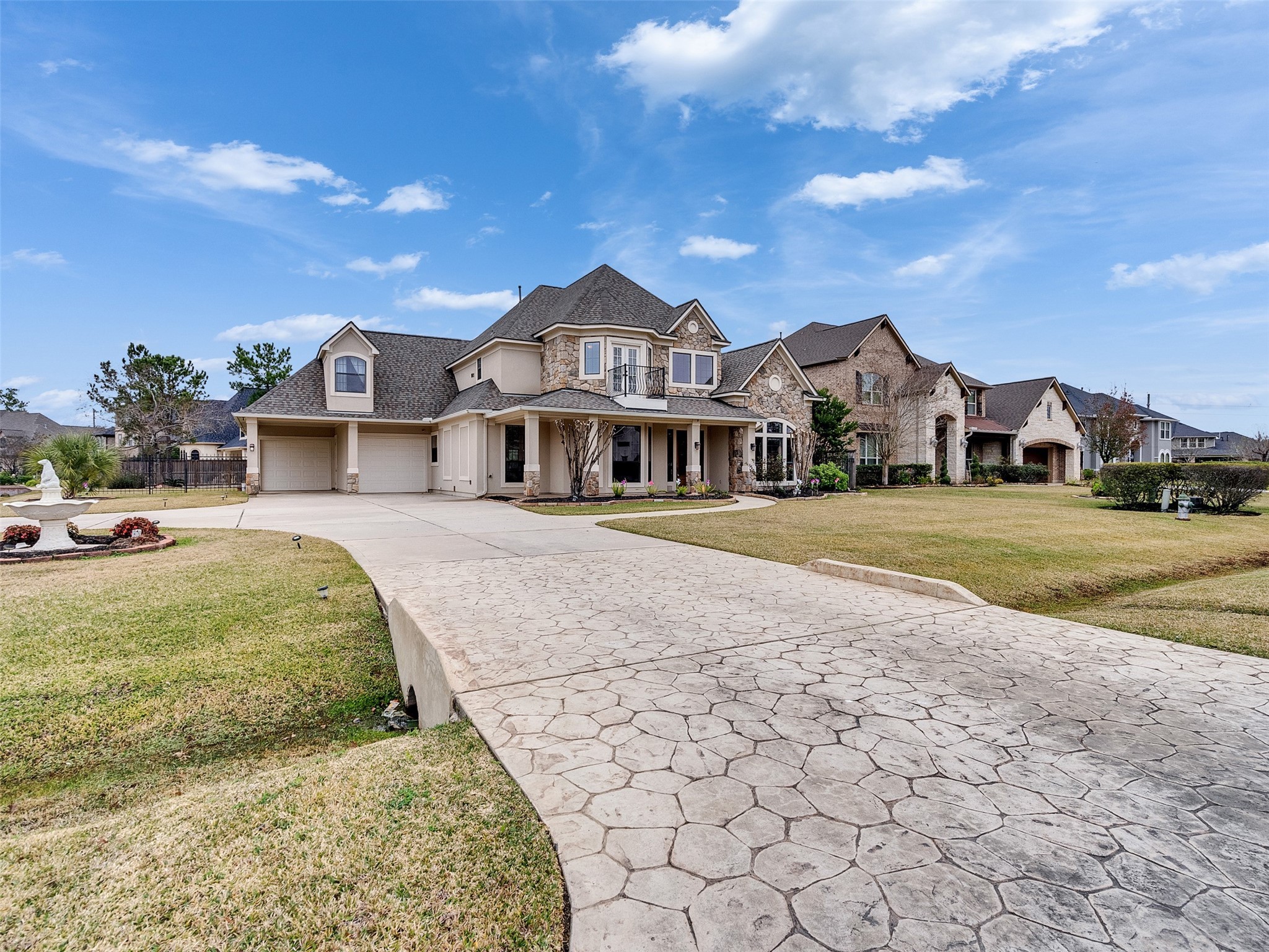 6914 Sandwedge Point Court Spring, TX 77389 - Photo 45 of 50 Elegant two-story home with a stone facade and a spacious three-car garage. The property features a large, patterned concrete driveway and well-maintained landscaping, set in a picturesque neighborhood.