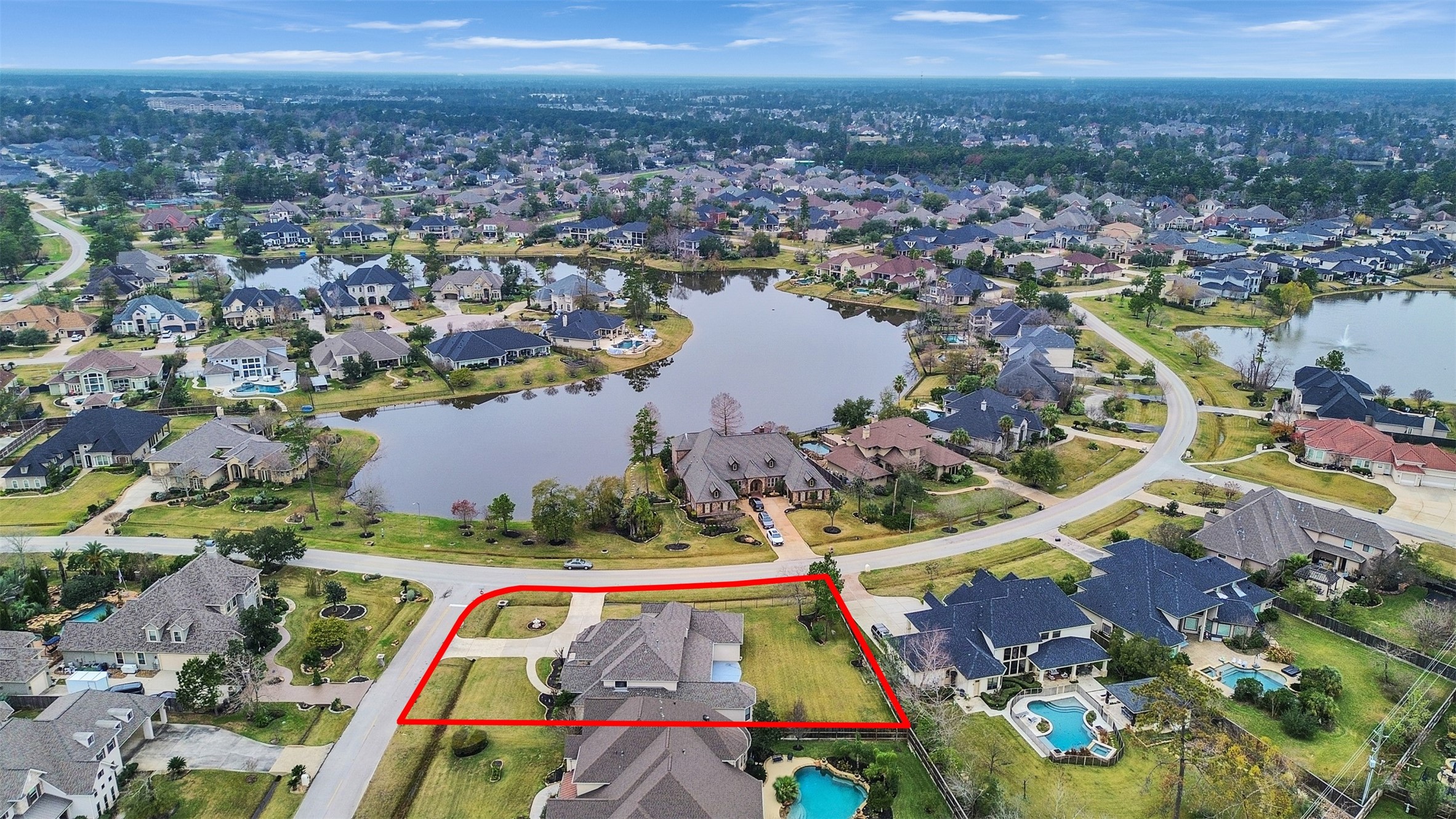 6914 Sandwedge Point Court Spring, TX 77389 - Photo 5 of 50 This photo showcases a spacious home outlined in red, situated in a picturesque neighborhood with lush greenery and scenic water views. The property is in a well-planned community featuring large homes, landscaped yards, and nearby lakes, offering a serene and upscale living environment.