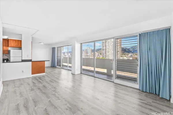 a view of an empty room with wooden floor and a window