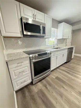 a kitchen with stainless steel appliances white cabinets and a stove top oven