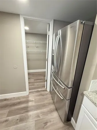 a view of a refrigerator in kitchen and an empty room