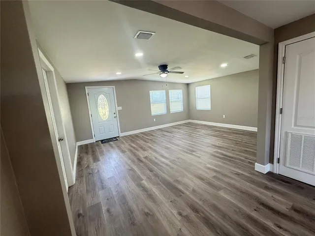 an empty room with wooden floor and windows