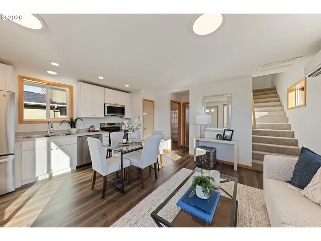 a living room with furniture dining table wooden floor and a view of kitchen
