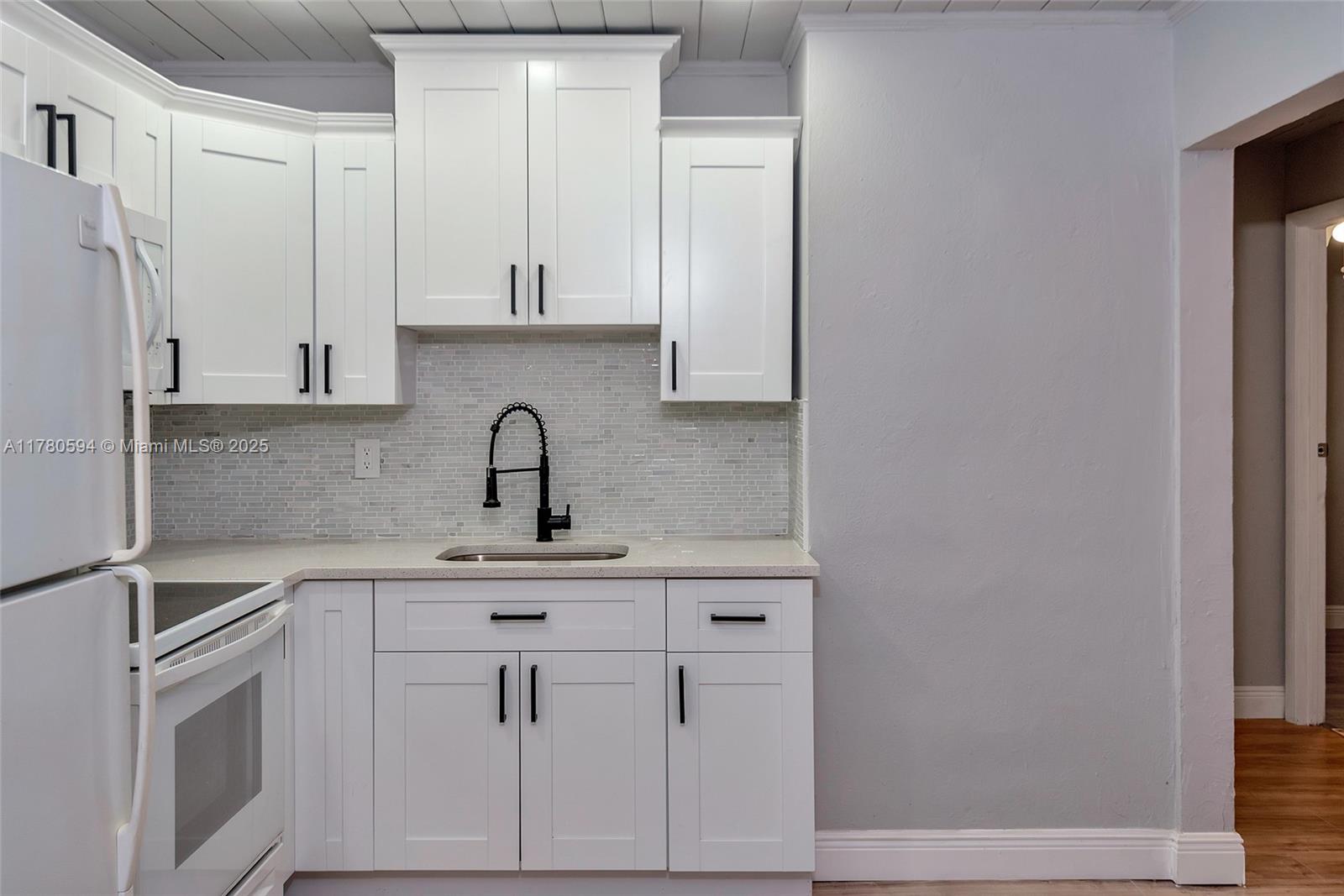 712 Division Avenue West Palm Beach, FL 33401 - Photo 21 of 37 a kitchen with white cabinets and white appliances