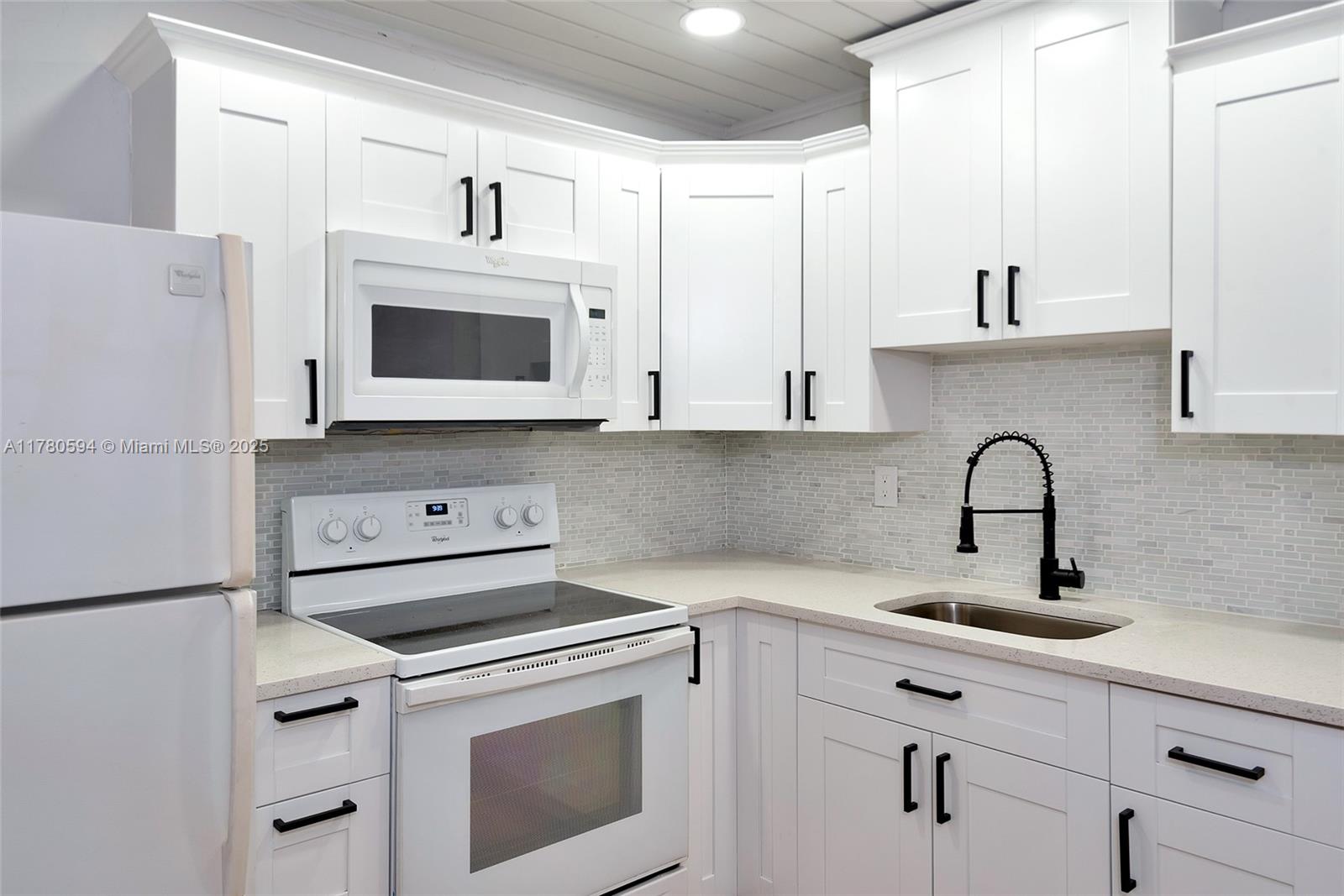 712 Division Avenue West Palm Beach, FL 33401 - Photo 22 of 37 a kitchen with white cabinets and white appliances