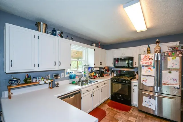 a kitchen with stainless steel appliances granite countertop a refrigerator a stove a sink dishwasher and white cabinets with wooden floor