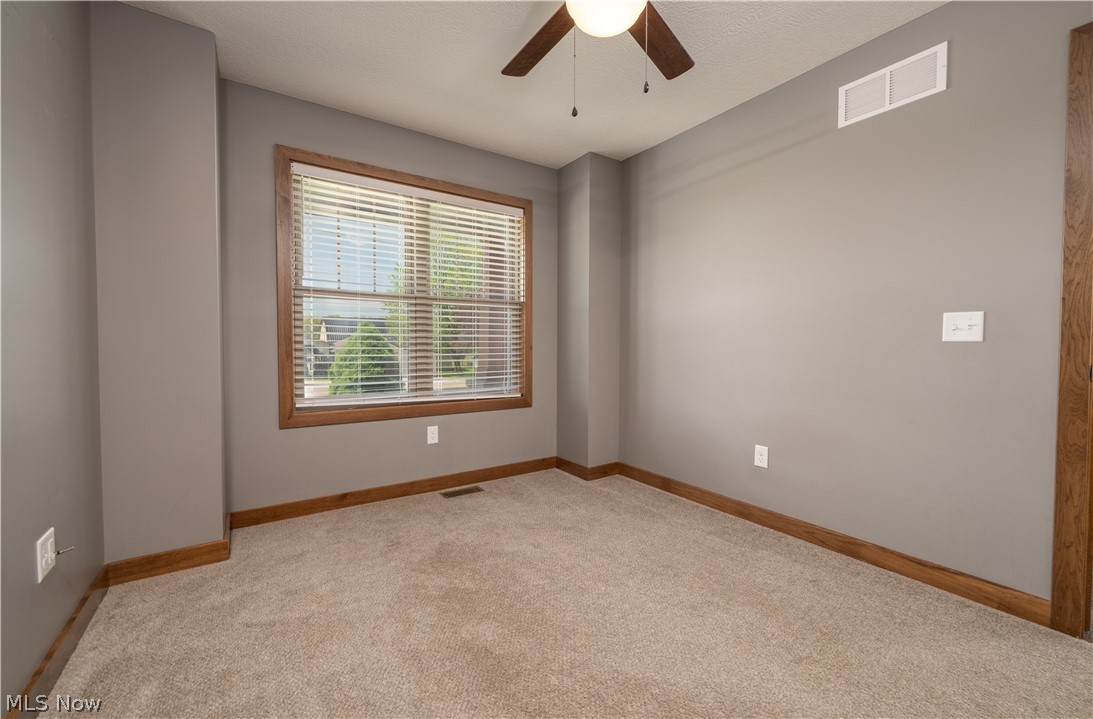 3515 Eastport Road Southeast Dennison, OH 44621 - Photo 21 of 41 Neutral-toned room featuring a window with wood trim and blinds, a ceiling fan, and carpeted flooring