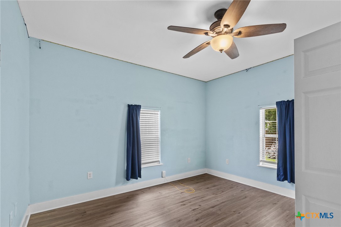 905 North Navarro Street Victoria, TX 77901 - Photo 16 of 28 an empty room with wooden floor chandelier fan and windows