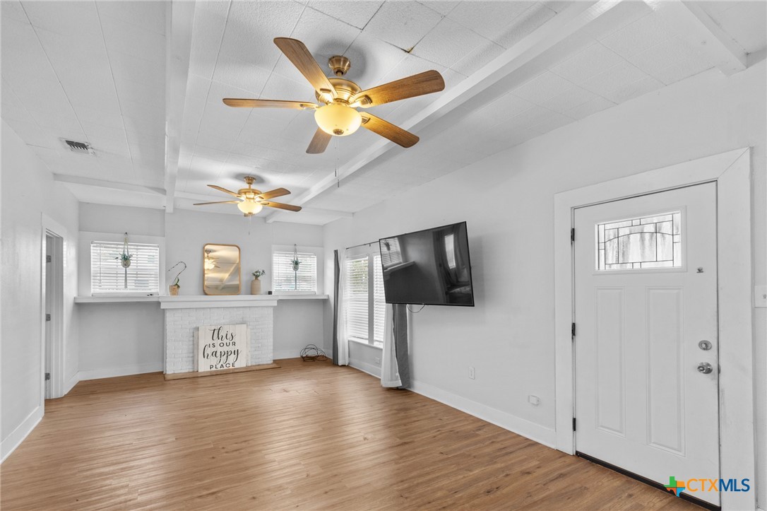 905 North Navarro Street Victoria, TX 77901 - Photo 9 of 28 a view of a livingroom with a flat screen tv wooden floor and a ceiling fan