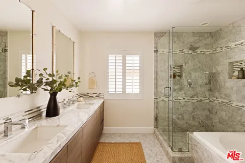 a bathroom with a granite countertop sink a large mirror a bathtub and shower