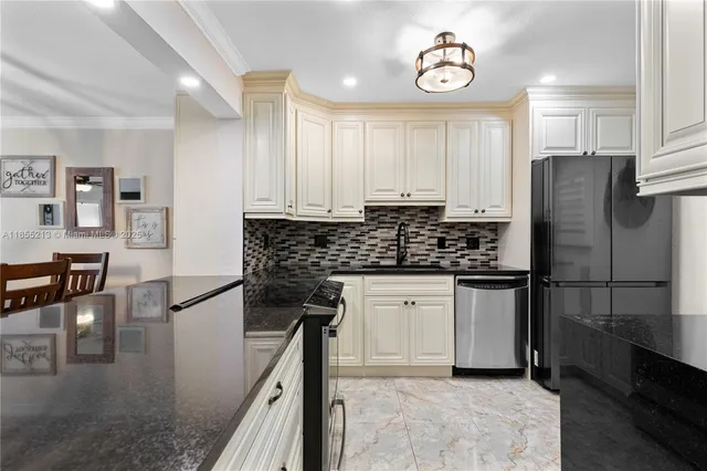 a kitchen with stainless steel appliances granite countertop a refrigerator a stove and white cabinets with wooden floor