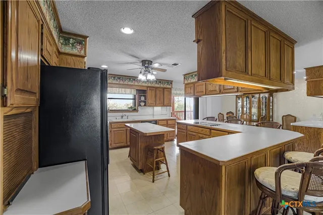 a kitchen with stainless steel appliances granite countertop a sink and dishwasher refrigerator stove with wooden cabinets