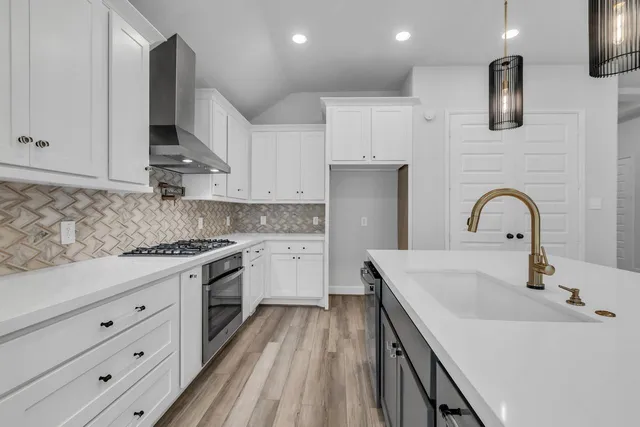 a kitchen with granite countertop a sink stainless steel appliances and cabinets