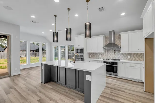 a large kitchen with stainless steel appliances kitchen island granite countertop a stove a sink and a wooden floors