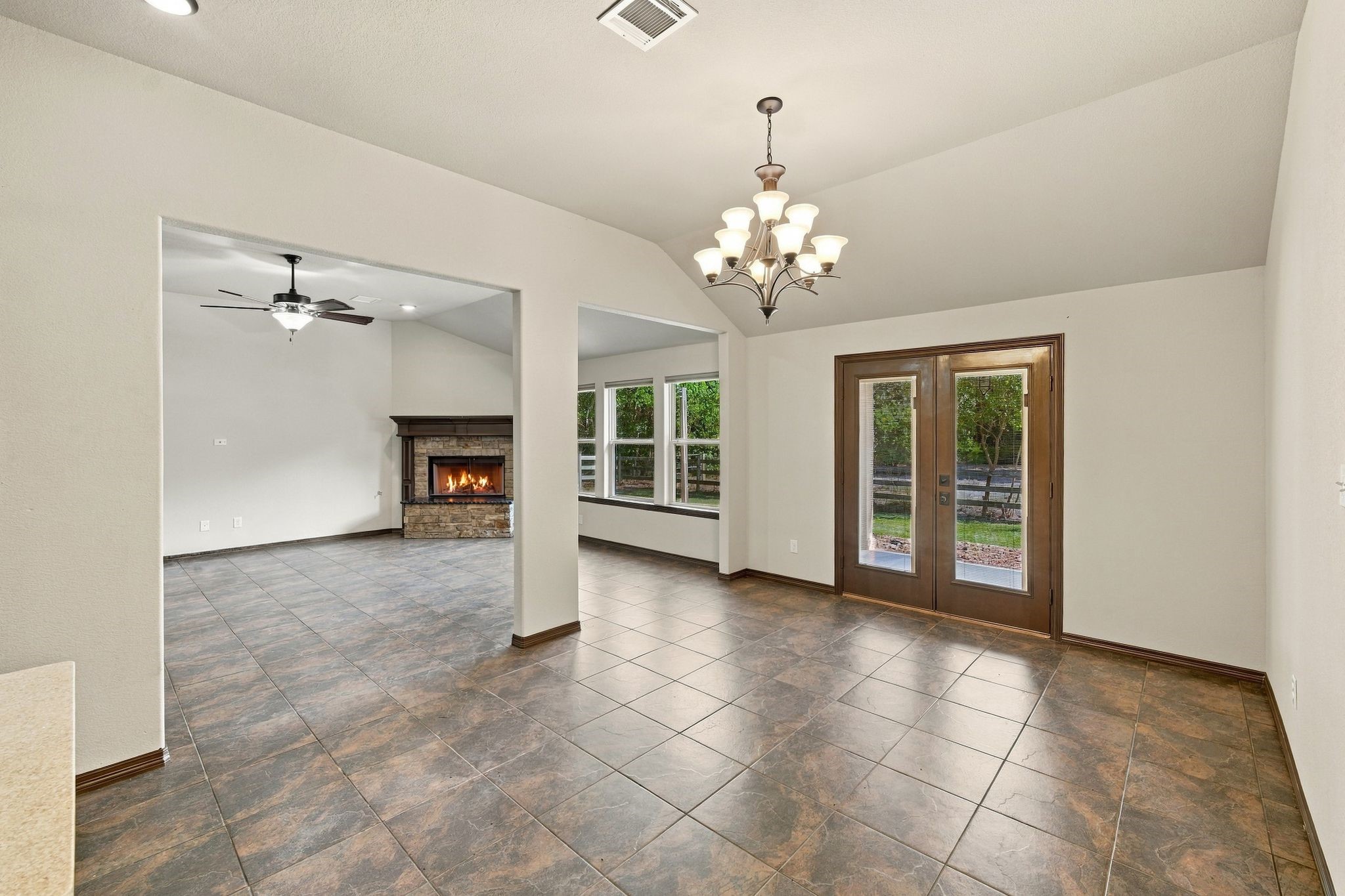 7049 Pine Shadows Road Cleveland, TX 77328 - Photo 11 of 49 Spacious living area featuring tile flooring, a cozy fireplace, and elegant French doors leading to a serene outdoor space.