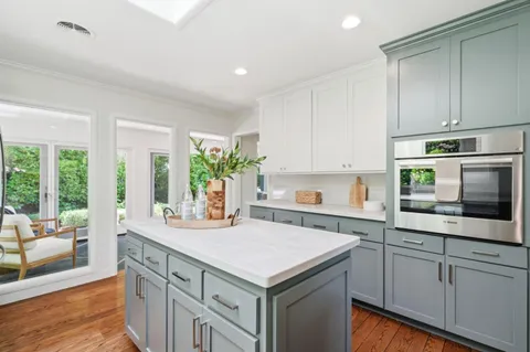 a kitchen with a stove cabinets and living room