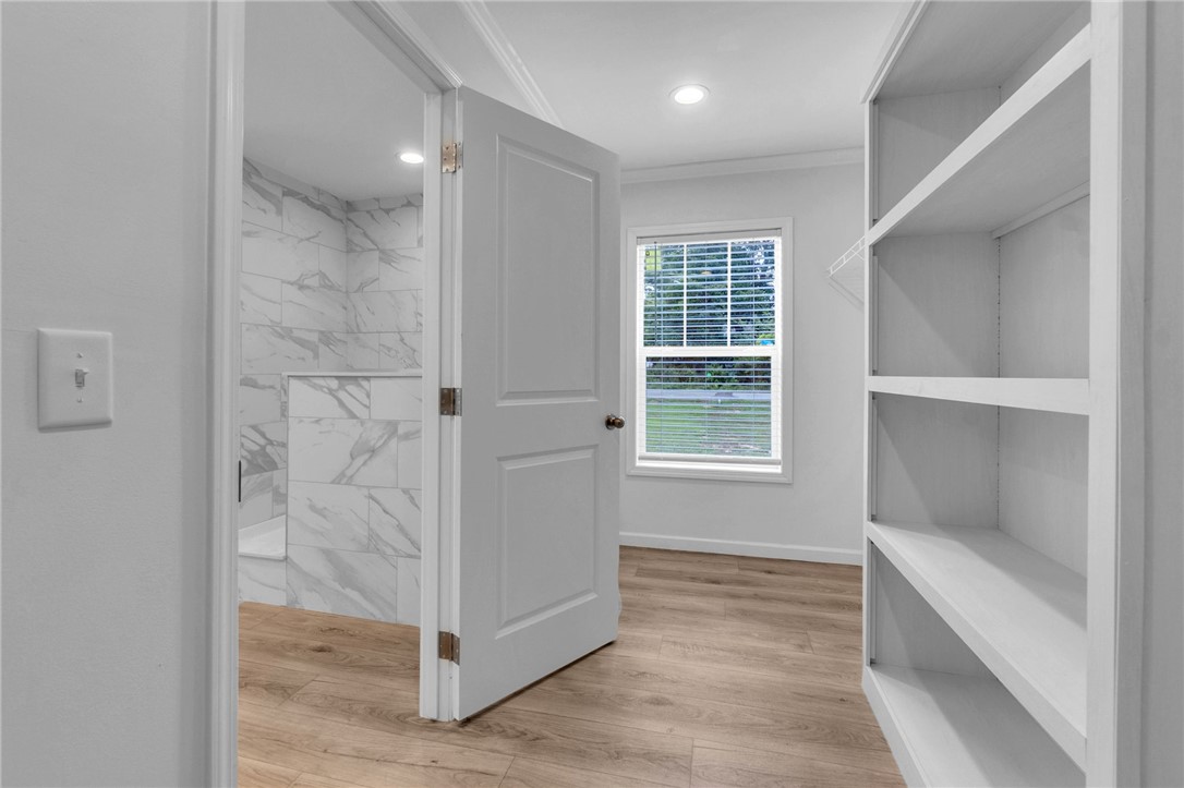 108 Old River Road Iva, SC 29655 - Photo 15 of 31 A well-lit interior offers durable wood flooring and practical built-in shelving, complemented by an adjoining bathroom with modern tile.