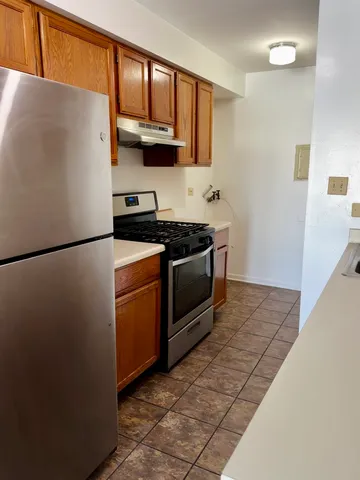 a kitchen with stainless steel appliances granite countertop a refrigerator a stove a sink and a microwave