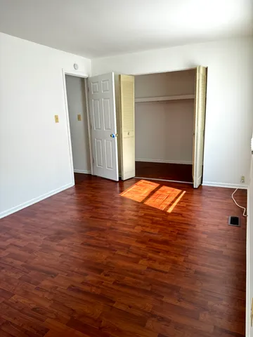 a view of an empty room with wooden floor and closet