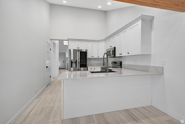 6969 South 855 East Midvale, UT 84047 - Photo 20 of 55 Modern kitchen featuring white shaker cabinetry, stainless steel appliances, light-toned wood-finish flooring, quartz countertops, and a kitchen island with an undermount sink
