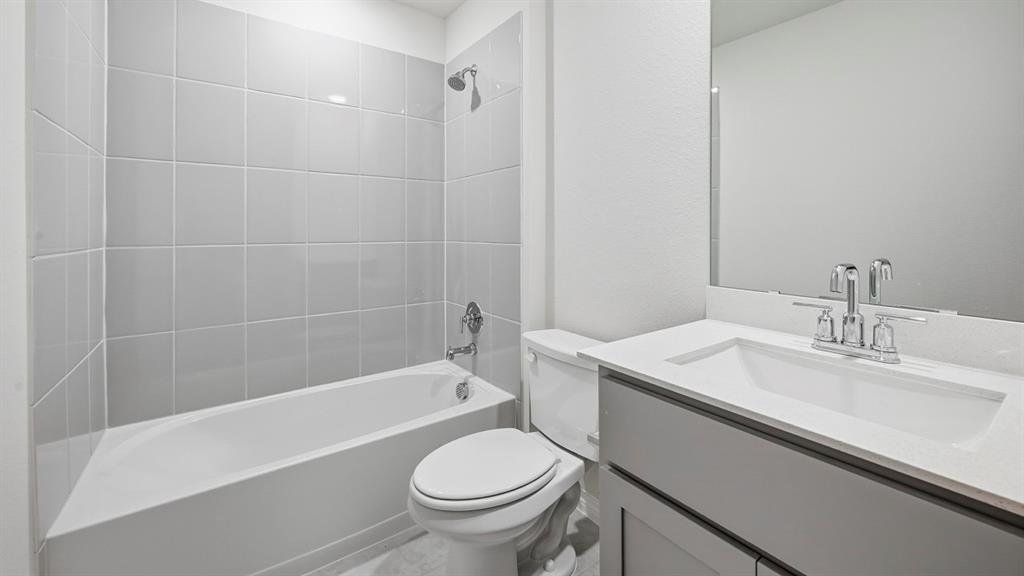 419 Epiphany Lane Lavon, TX 75166 - Photo 29 of 31 Bathroom featuring a bathtub with light gray subway tile surround, a single vanity with a white countertop, an undermount sink, and a framed mirror