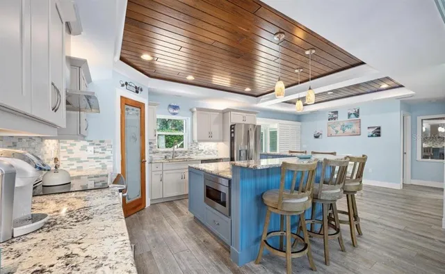 a kitchen with stainless steel appliances granite countertop a kitchen island hardwood floor and a sink