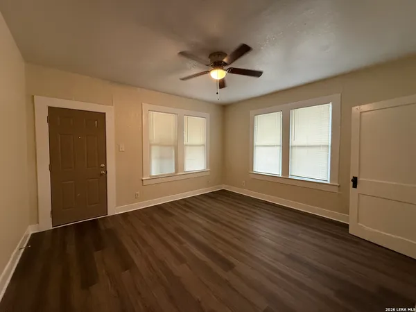 a view of an empty room with wooden floor and a window
