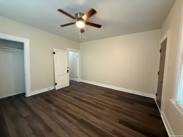 an empty room with wooden floor and ceiling fan