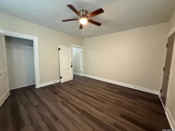 an empty room with wooden floor and a ceiling fan