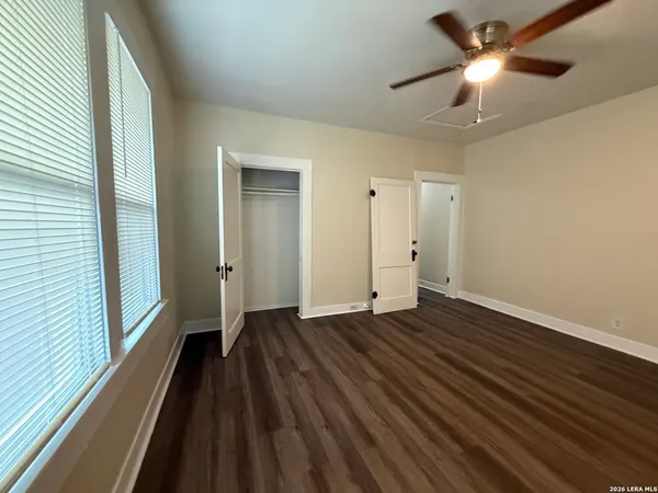 a view of empty room with wooden floor and fan