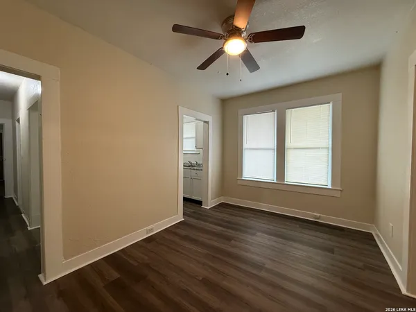 a view of an empty room with wooden floor and a window