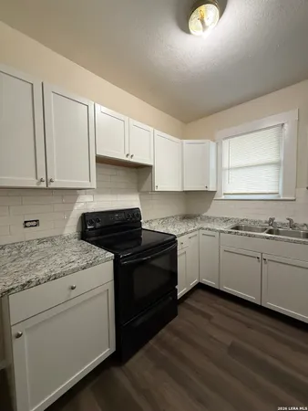 a kitchen with granite countertop white cabinets and white appliances