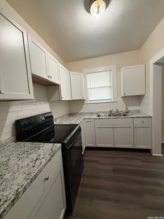 a kitchen with granite countertop a sink a stove and cabinets
