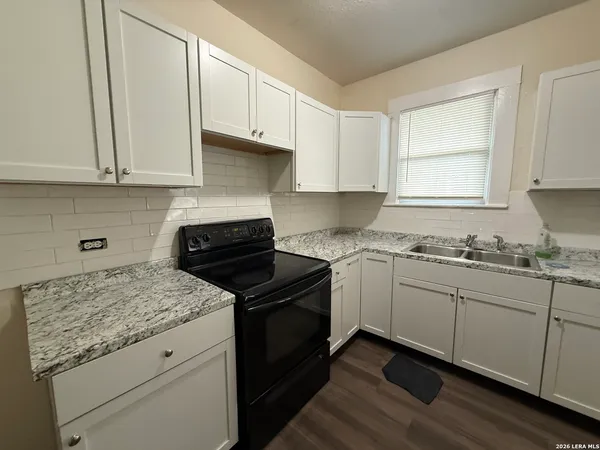 a kitchen with granite countertop white cabinets and a sink