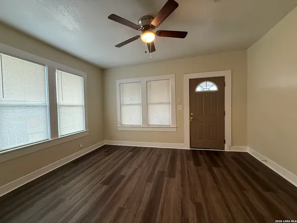 a view of an empty room with wooden floor and a window