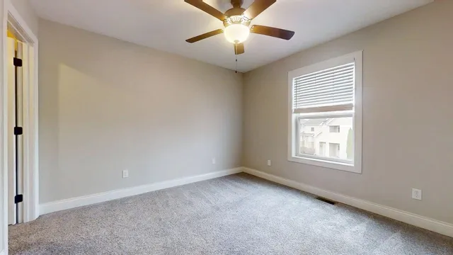 an empty room with a ceiling fan and a window
