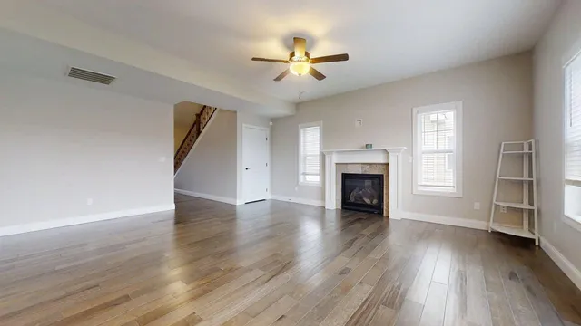 an empty room with wooden floor fireplace and windows