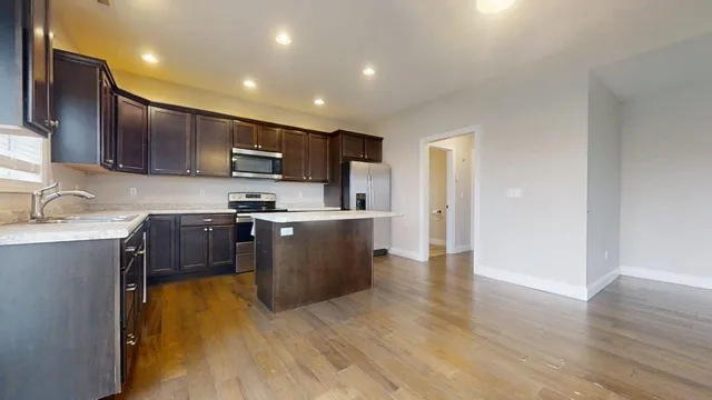 a kitchen with stainless steel appliances granite countertop white cabinets a sink a stove a refrigerator and a microwave