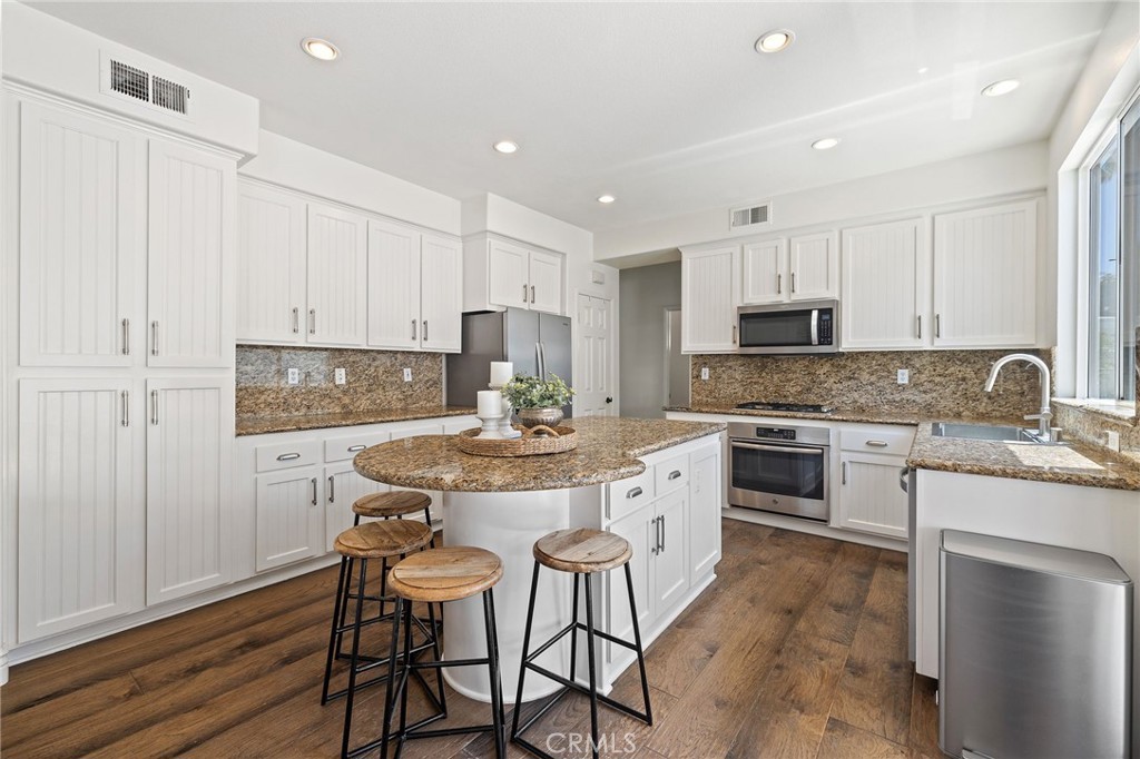 8 Danbury Ladera Ranch, CA 92694 - Photo 15 of 57 a kitchen with kitchen island granite countertop white cabinets and stainless steel appliances