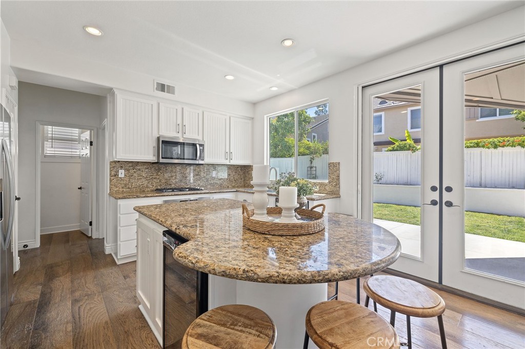8 Danbury Ladera Ranch, CA 92694 - Photo 17 of 57 a kitchen with a stove a sink a kitchen island with chairs and wooden floor