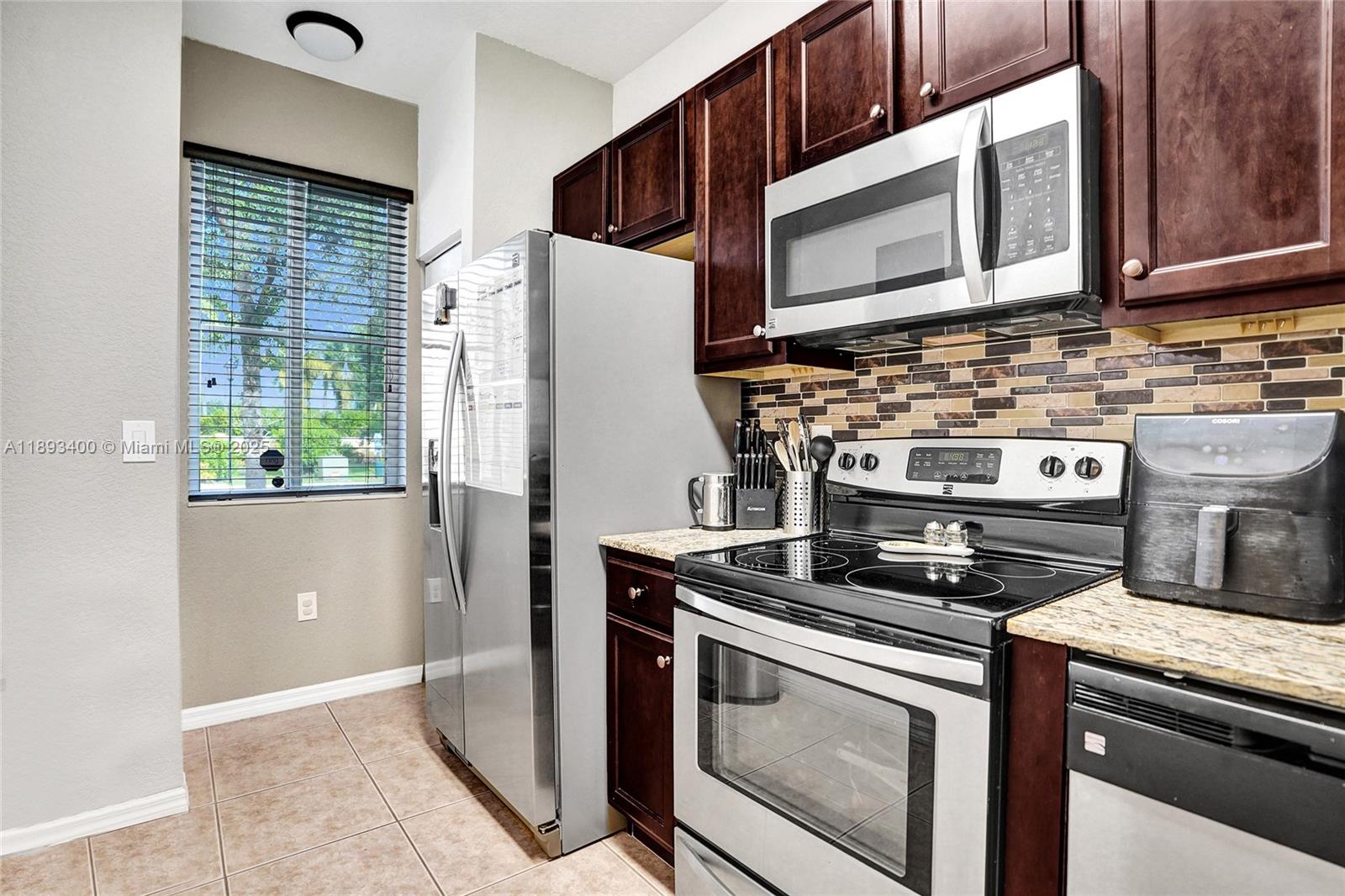 1832 Southwest 89th Terrace Miramar, FL 33025 - Photo 8 of 28 a kitchen with stainless steel appliances wooden cabinets sink and stove top oven