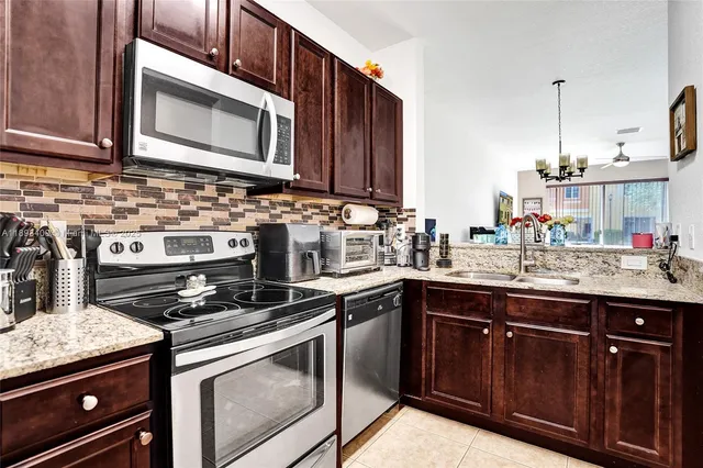 a kitchen with stainless steel appliances granite countertop a stove a microwave and wooden cabinets