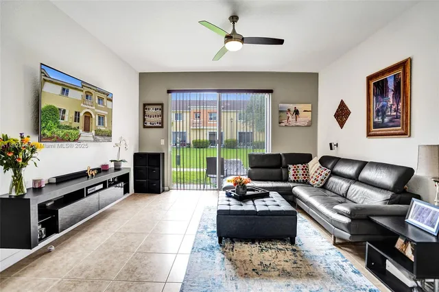 a living room with furniture a flat screen tv and a floor to ceiling window