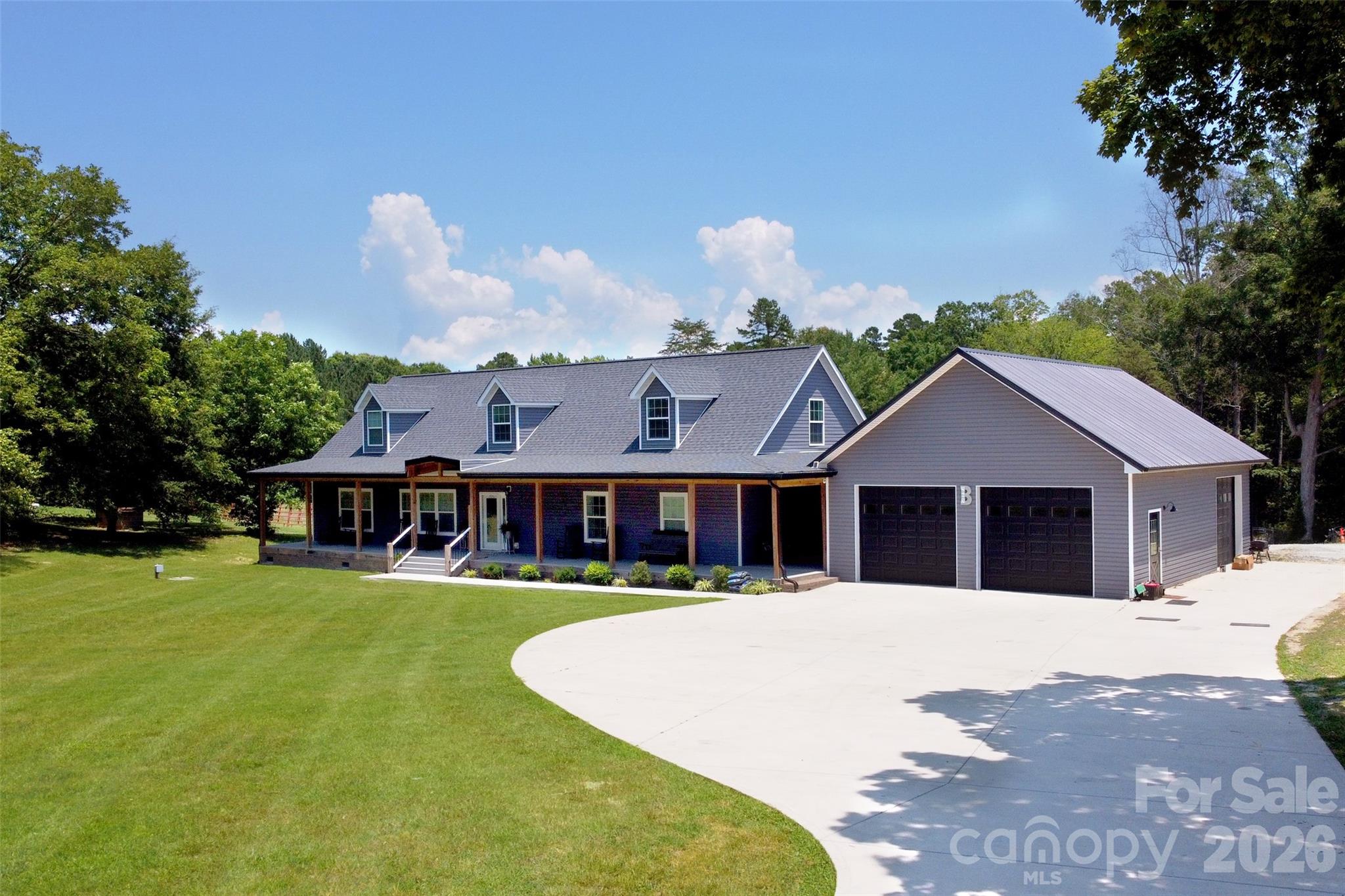 a view of a house with a big yard and large trees